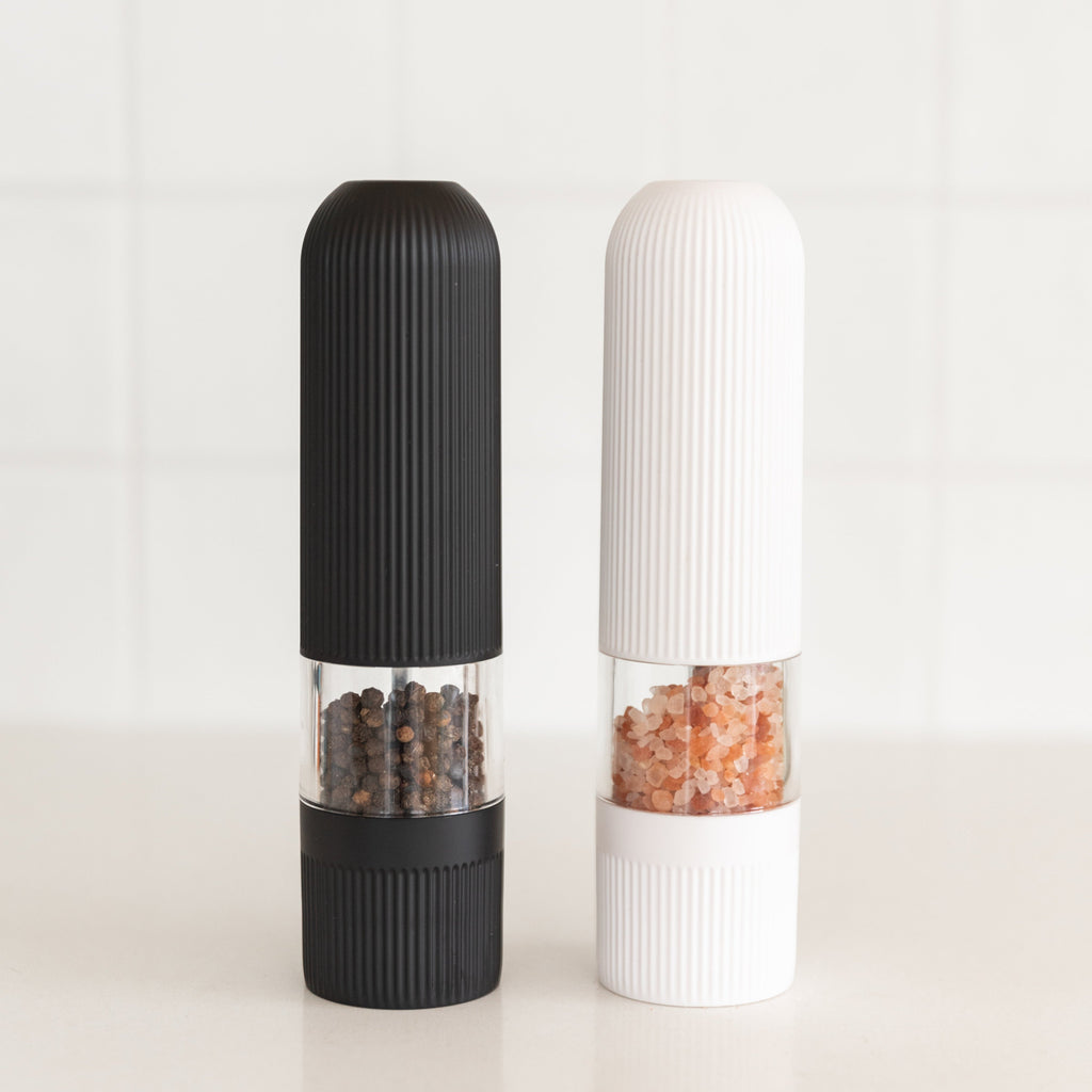 Black and white pepper grinders on a light background