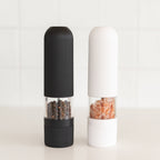 Black and white pepper grinders on a light background