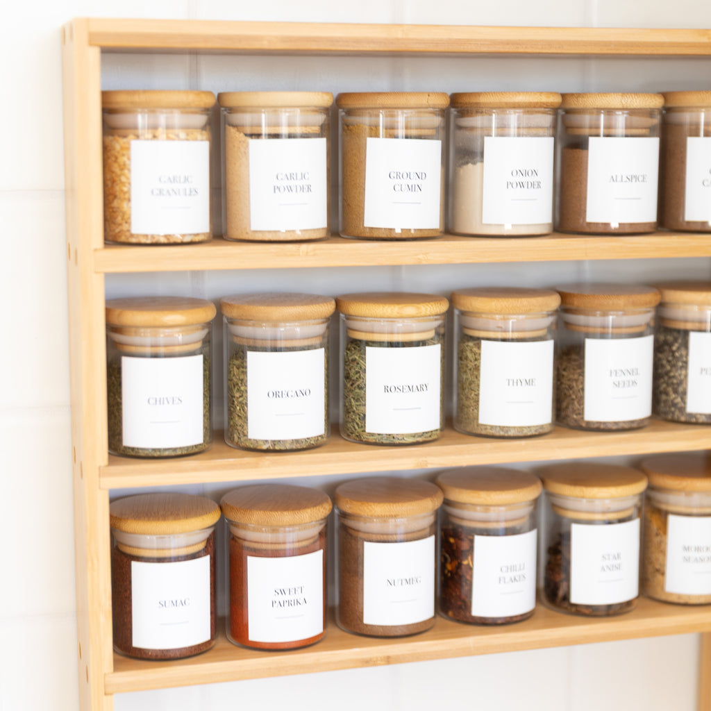 Wooden shelf with jars labeled with white labels on a light background