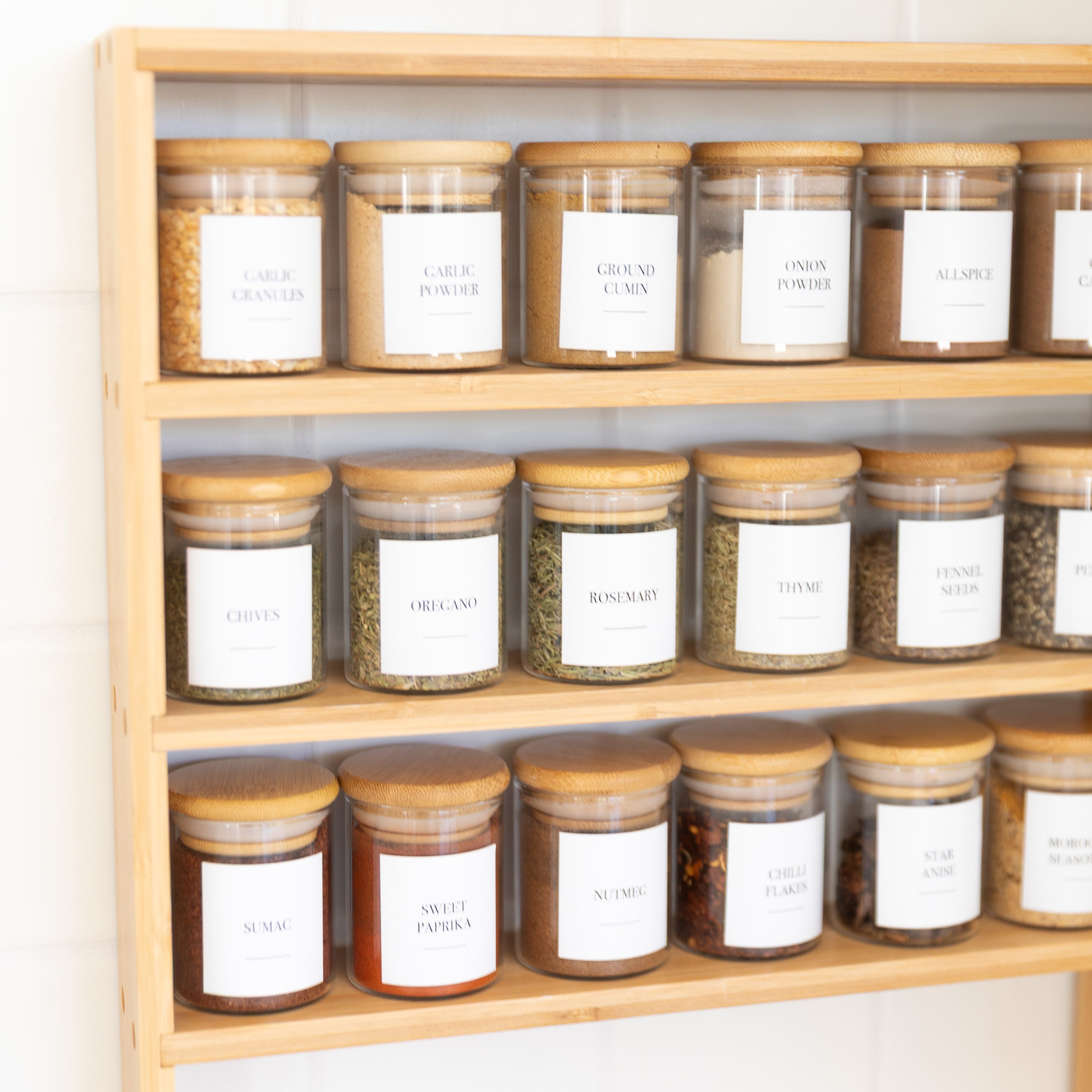 Wooden shelf with jars labeled with white labels on a light background
